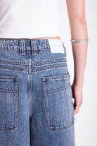 Vintage wash oversized baggy colossus jeans with silver eyelet and stud hardware detail, worn by model
