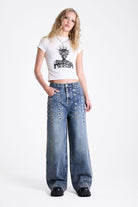 Vintage wash oversized baggy colossus jeans with silver eyelet and stud hardware detail, worn by model