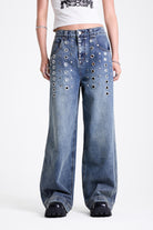 Vintage wash oversized baggy colossus jeans with silver eyelet and stud hardware detail, worn by model
