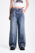 Vintage wash oversized baggy colossus jeans with silver eyelet and stud hardware detail, worn by model