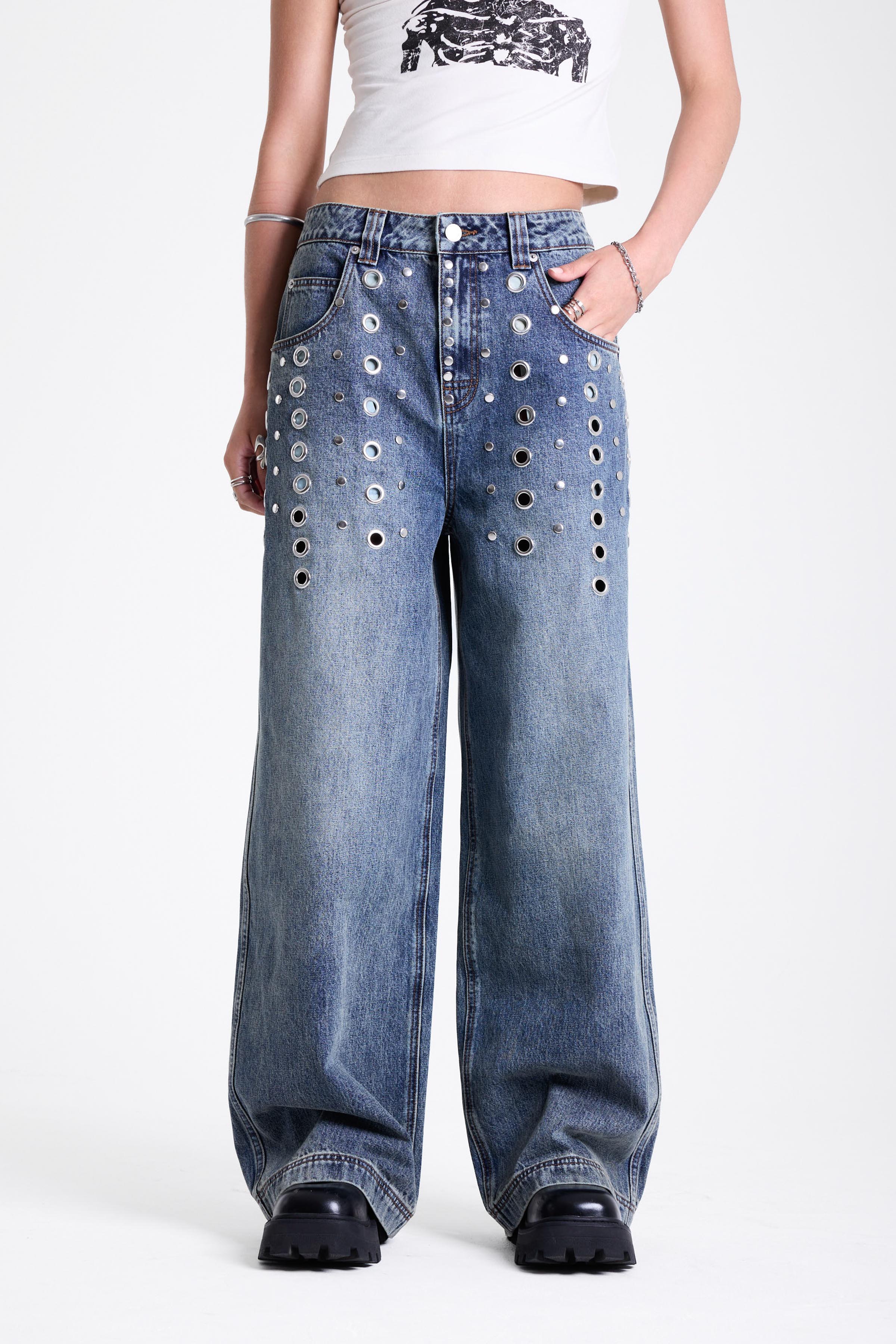 Vintage wash oversized baggy colossus jeans with silver eyelet and stud hardware detail, worn by model