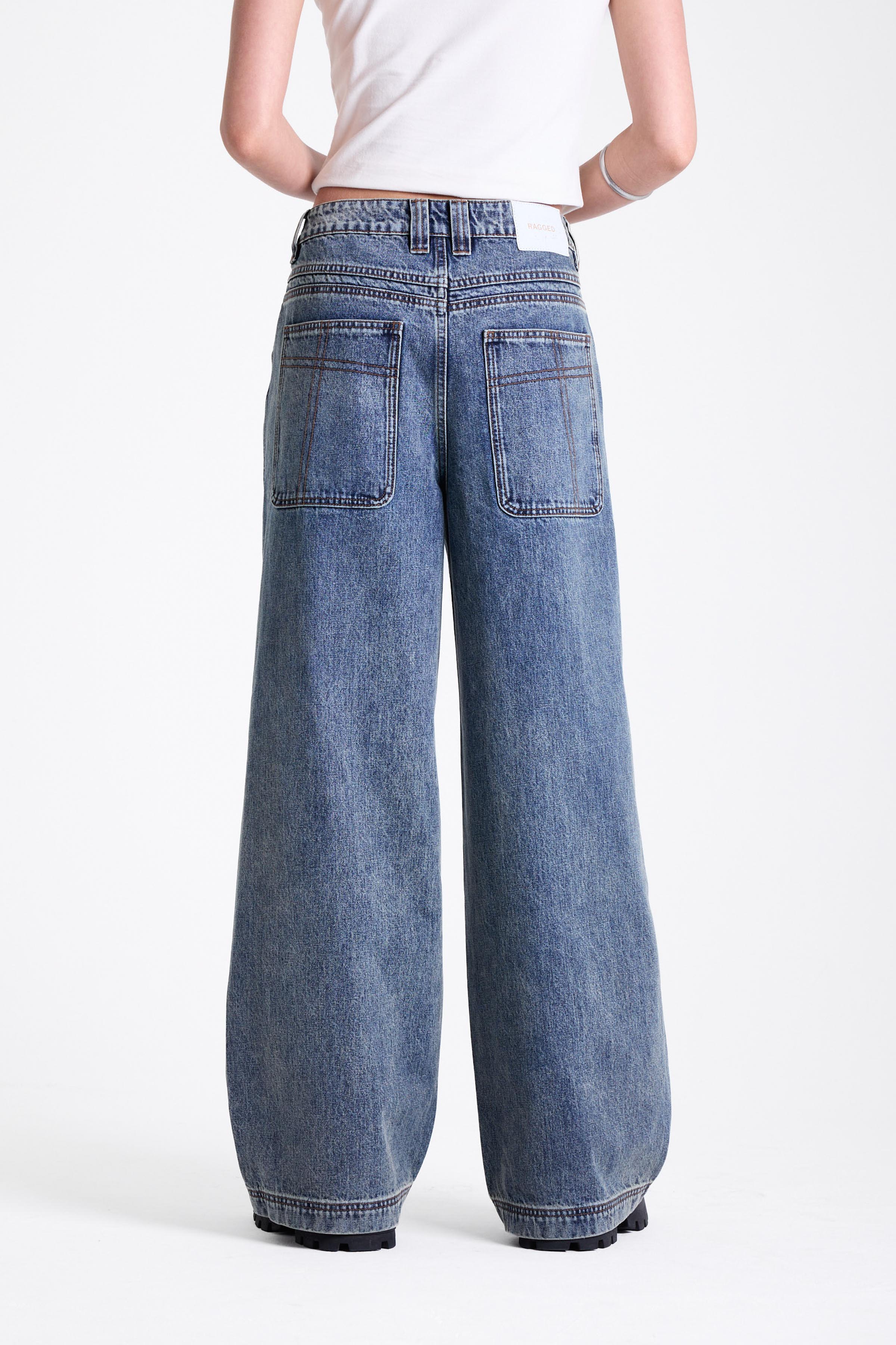 Vintage wash oversized baggy colossus jeans with silver eyelet and stud hardware detail, worn by model