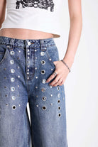 Vintage wash oversized baggy colossus jeans with silver eyelet and stud hardware detail, worn by model