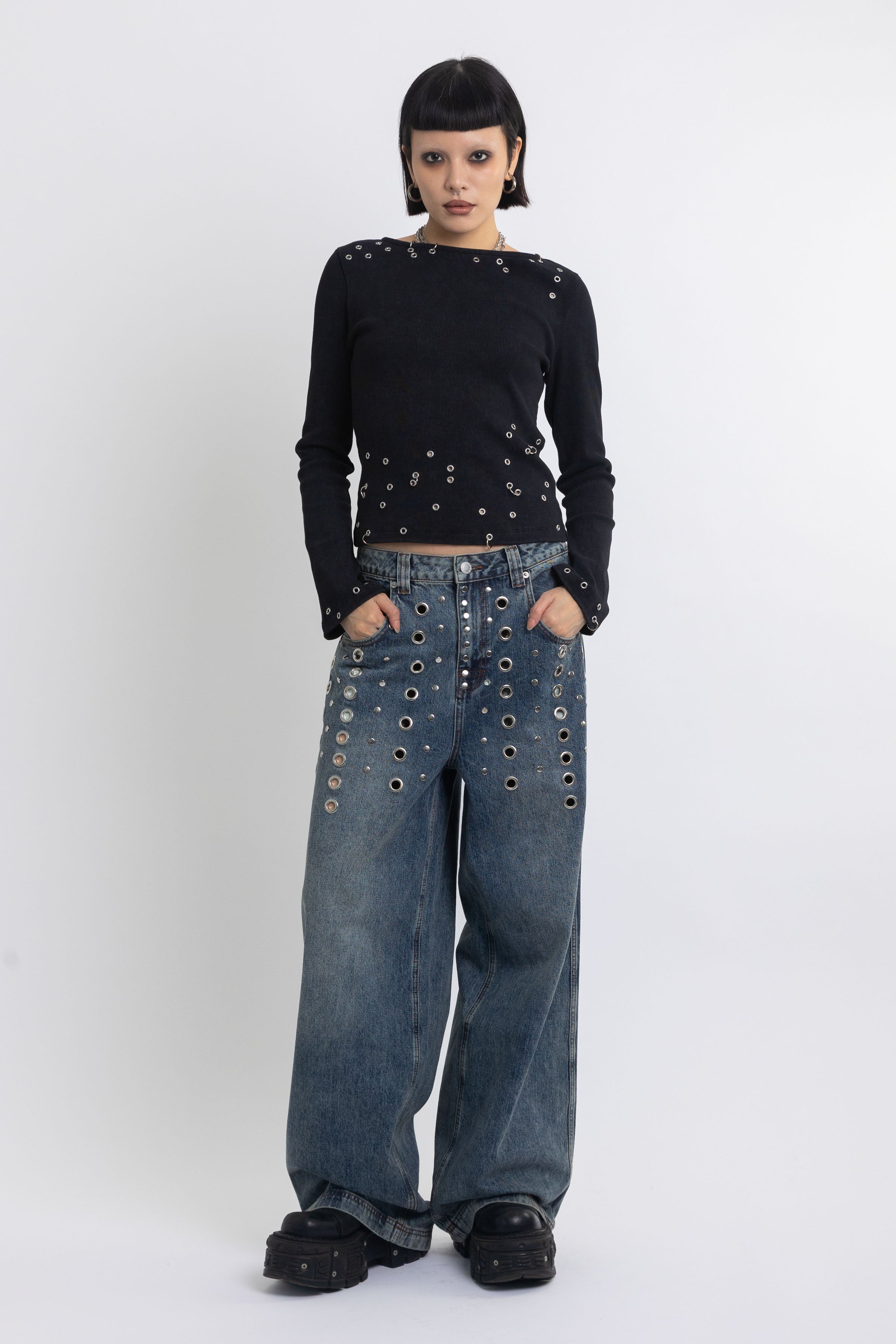 Mid blue wash ultra baggy colossus jeans with silver stud and eyelet hardware, worn by model