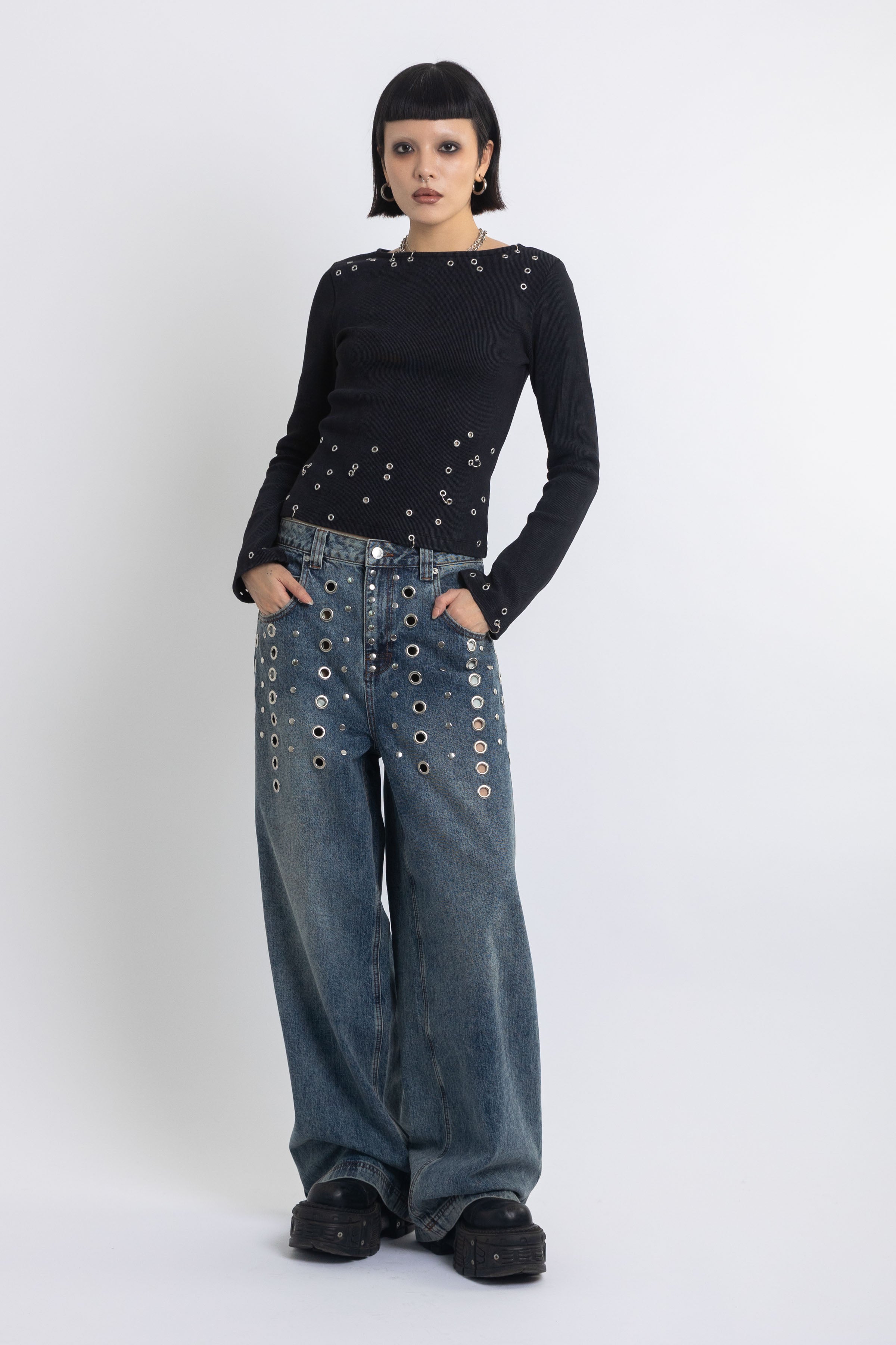 Mid blue wash ultra baggy colossus jeans with silver stud and eyelet hardware, worn by model
