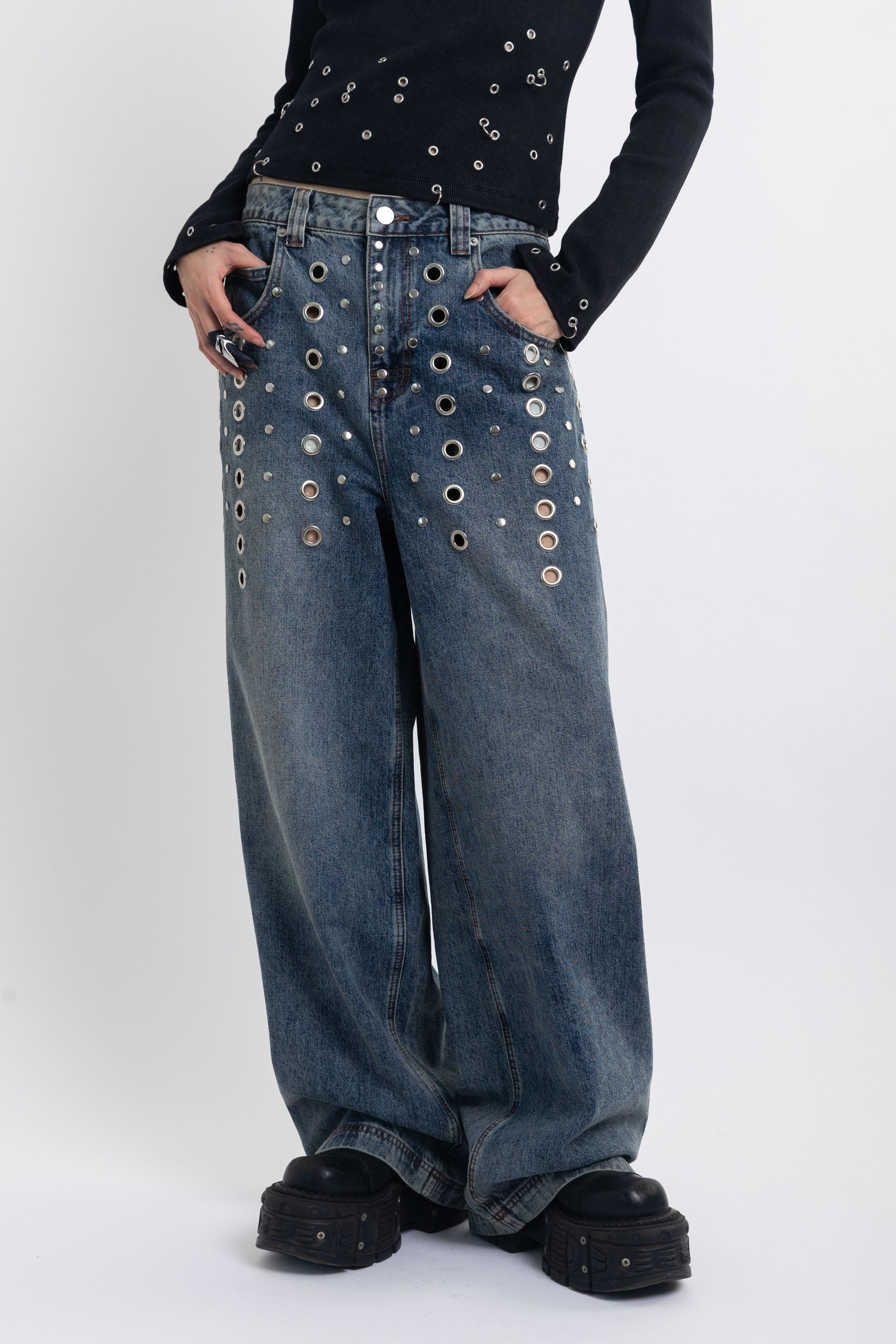 Mid blue wash ultra baggy colossus jeans with silver stud and eyelet hardware, worn by model