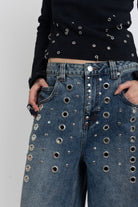 Mid blue wash ultra baggy colossus jeans with silver stud and eyelet hardware, worn by model