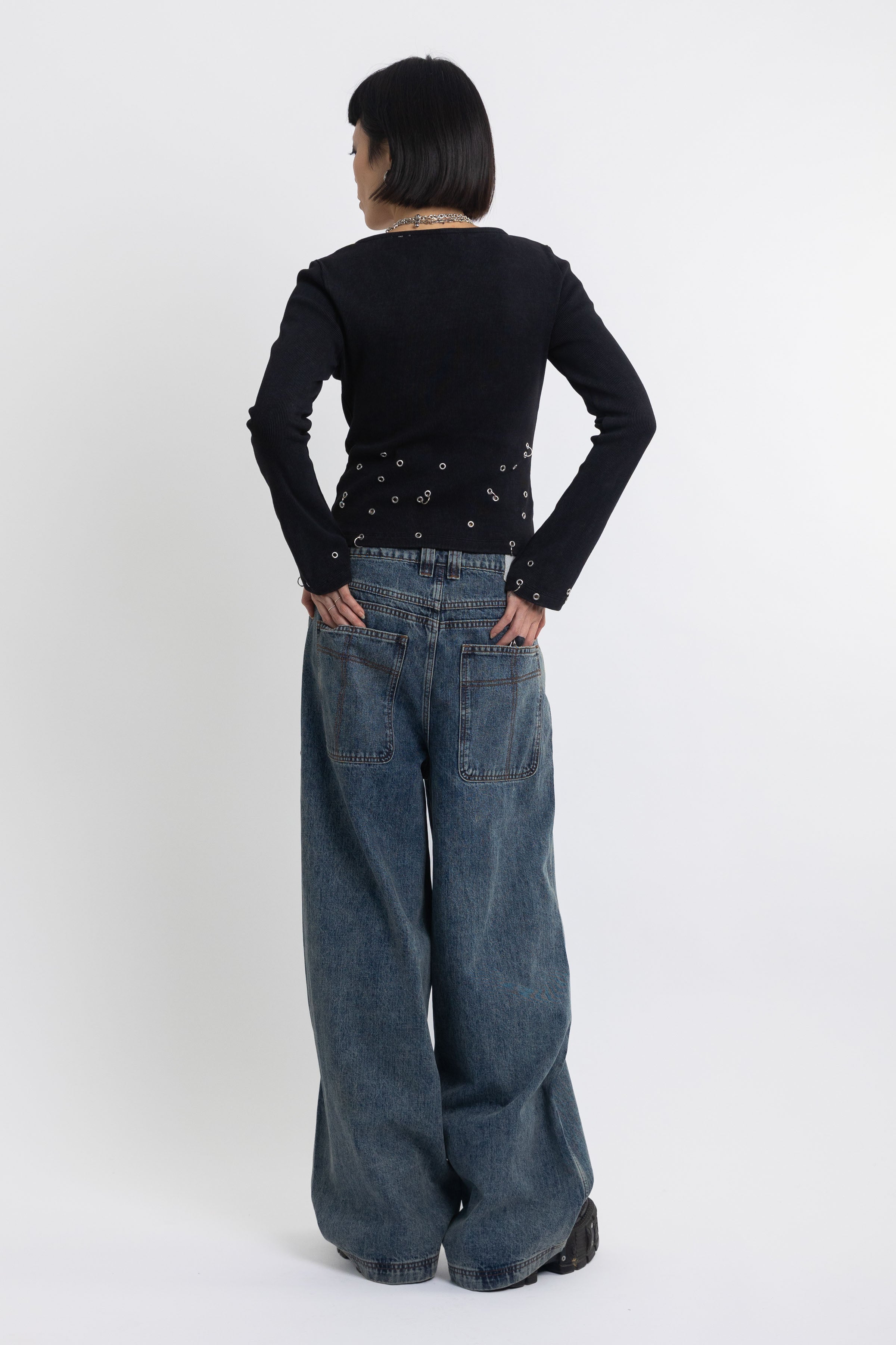 Mid blue wash ultra baggy colossus jeans with silver stud and eyelet hardware, worn by model