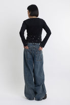 Mid blue wash ultra baggy colossus jeans with silver stud and eyelet hardware, worn by model