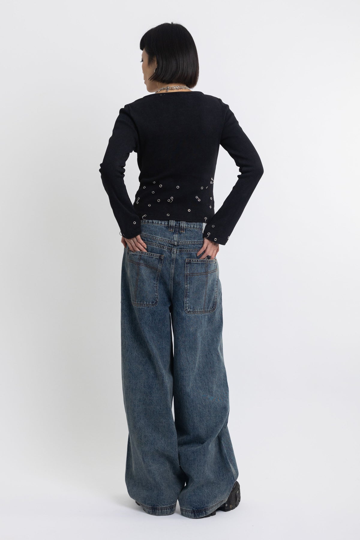 Mid blue wash ultra baggy colossus jeans with silver stud and eyelet hardware, worn by model