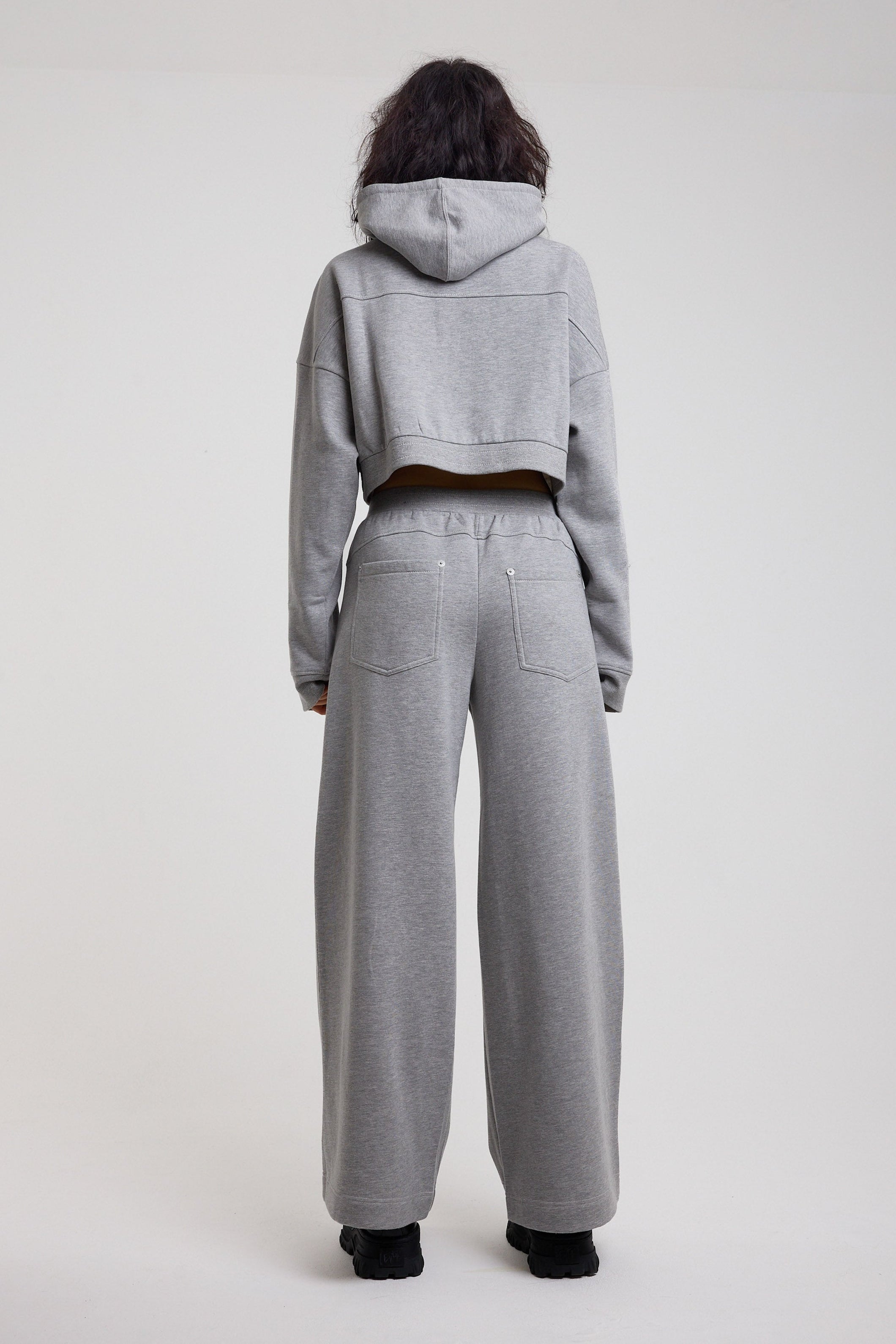 Back image of grey wide leg trackpants with silver hardware clasp detail, worn by model