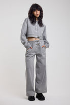 Grey wide leg trackpants with silver hardware clasp detail, worn by model