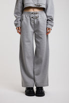 Grey wide leg trackpants with silver hardware clasp detail, worn by model
