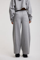Back image of grey wide leg trackpants with silver hardware clasp detail, worn by model