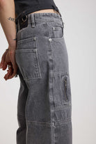 Close up showing zip and panelling detail on washed grey baggy cropped carpenter jeans, worn by model