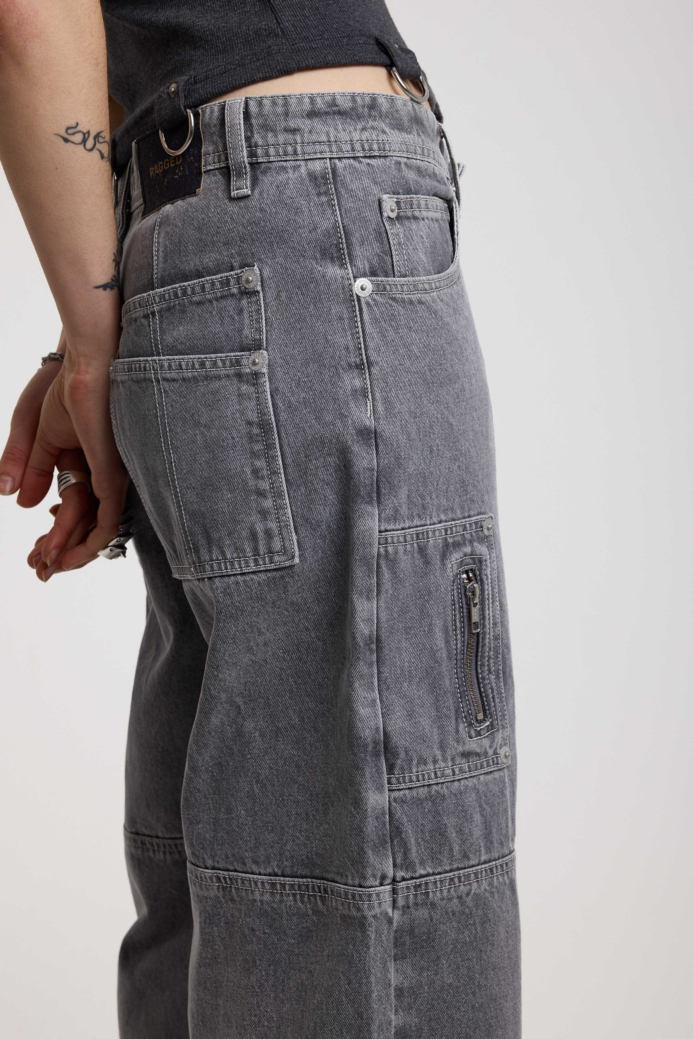Close up showing zip and panelling detail on washed grey baggy cropped carpenter jeans, worn by model