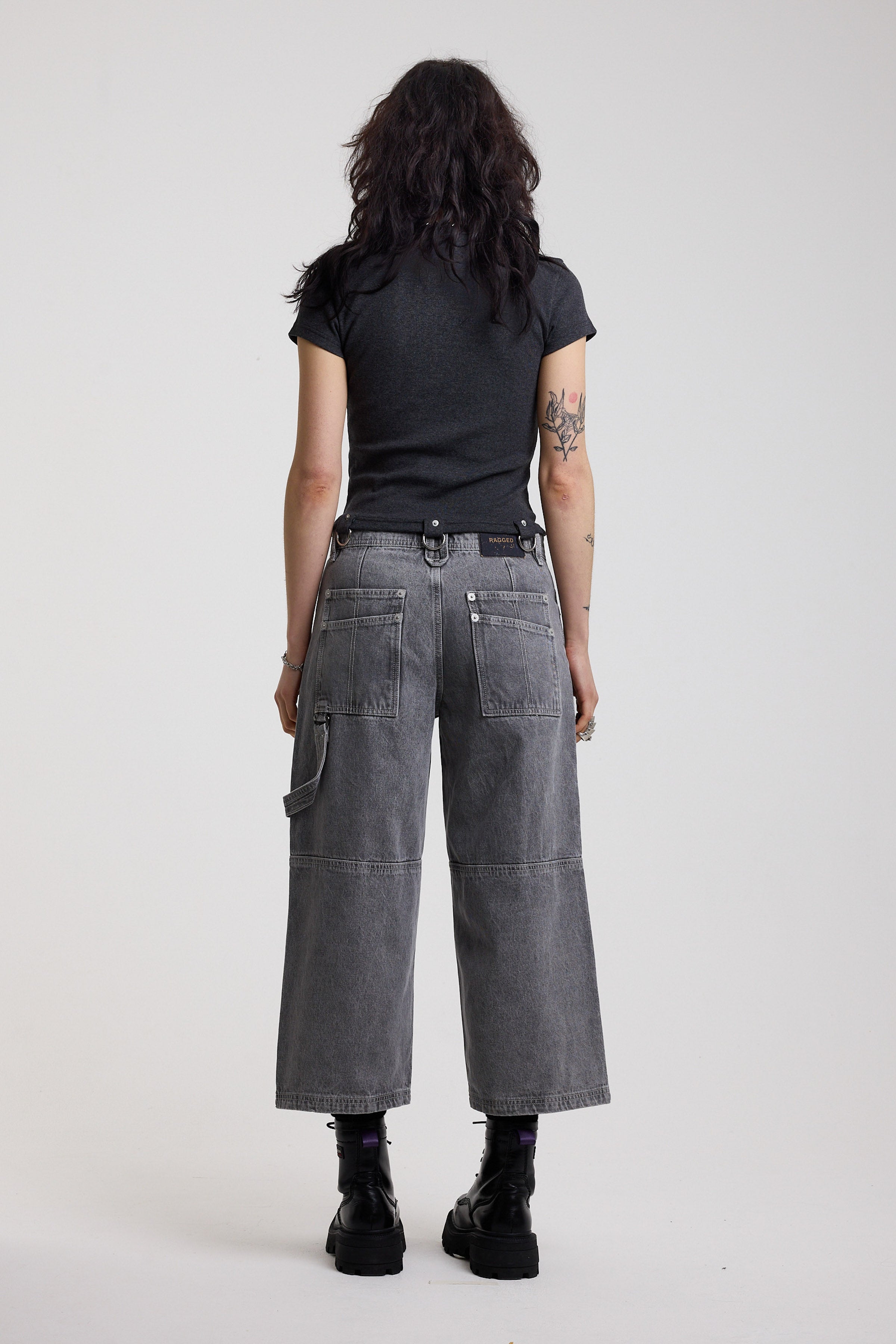 Back of washed grey baggy cropped carpenter jeans with hardware detail, worn by model