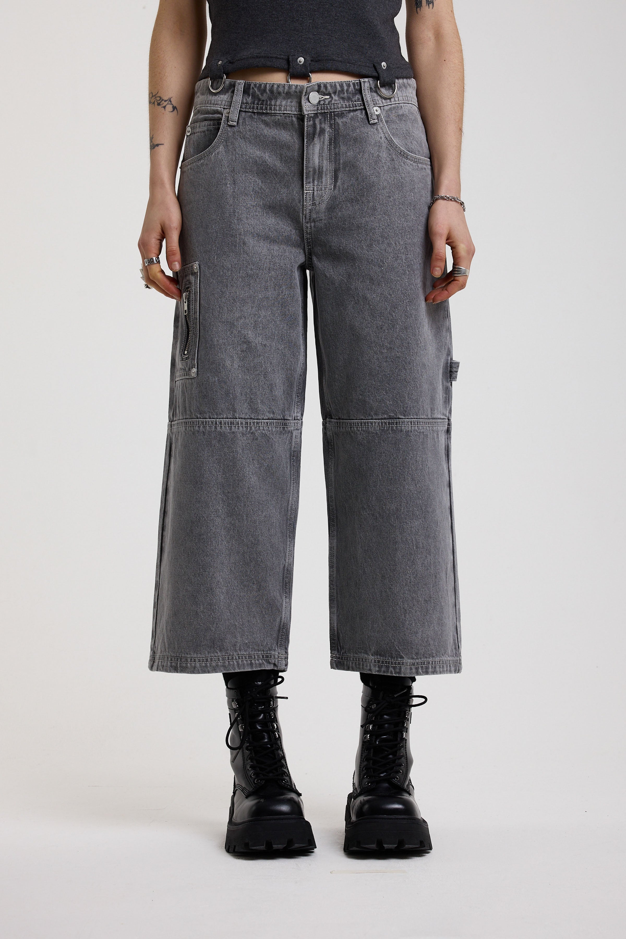 Washed grey baggy cropped carpenter jeans with hardware detail, worn by model