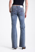 Vintage wash low rise flare jeans with exposed seam and stud detail, worn by model
