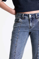 Vintage wash low rise flare jeans with exposed seam and stud detail, worn by model