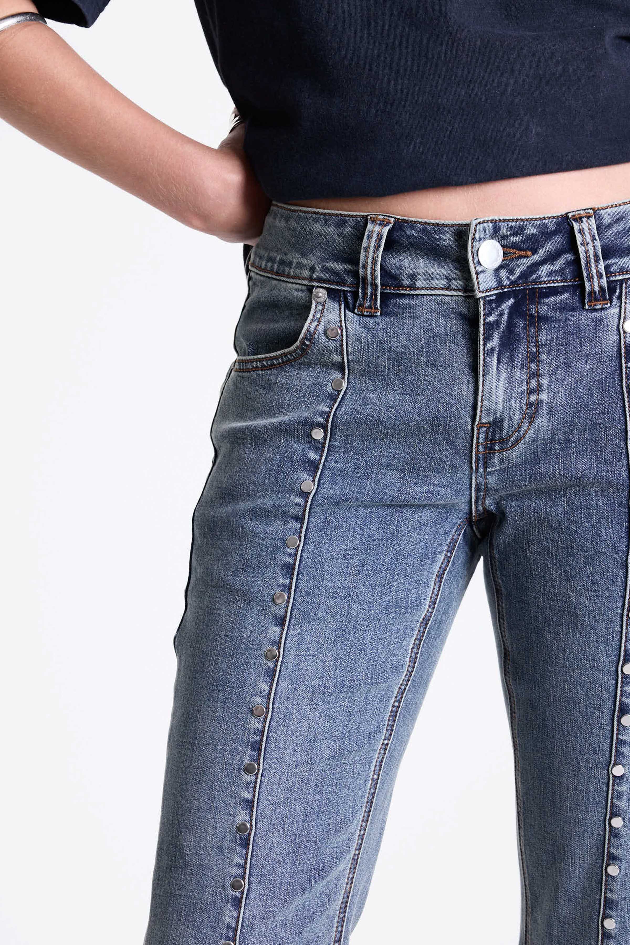 Vintage wash low rise flare jeans with exposed seam and stud detail, worn by model