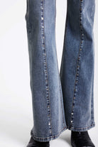 Vintage wash low rise flare jeans with exposed seam and stud detail, worn by model