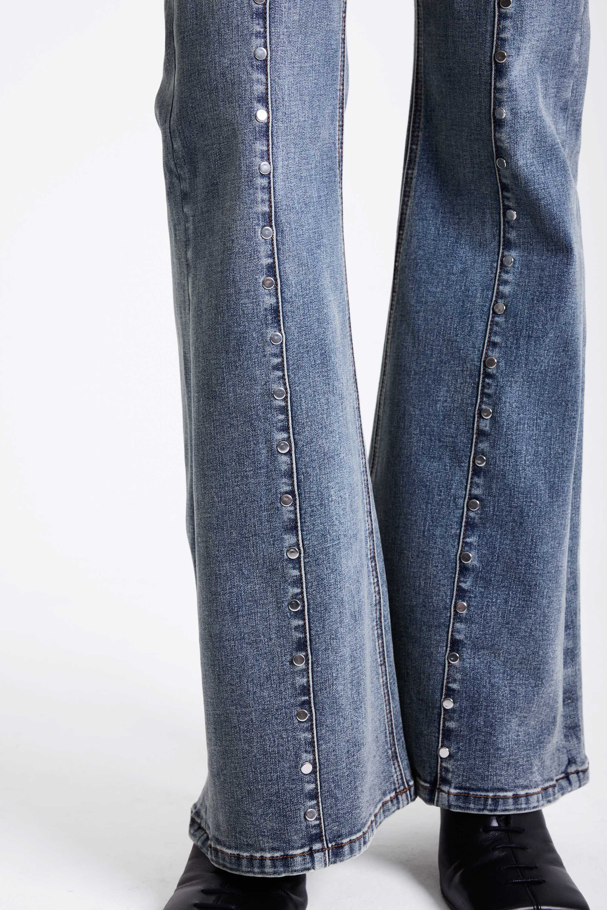 Vintage wash low rise flare jeans with exposed seam and stud detail, worn by model