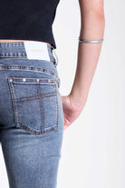 Vintage wash low rise flare jeans with exposed seam and stud detail, worn by model