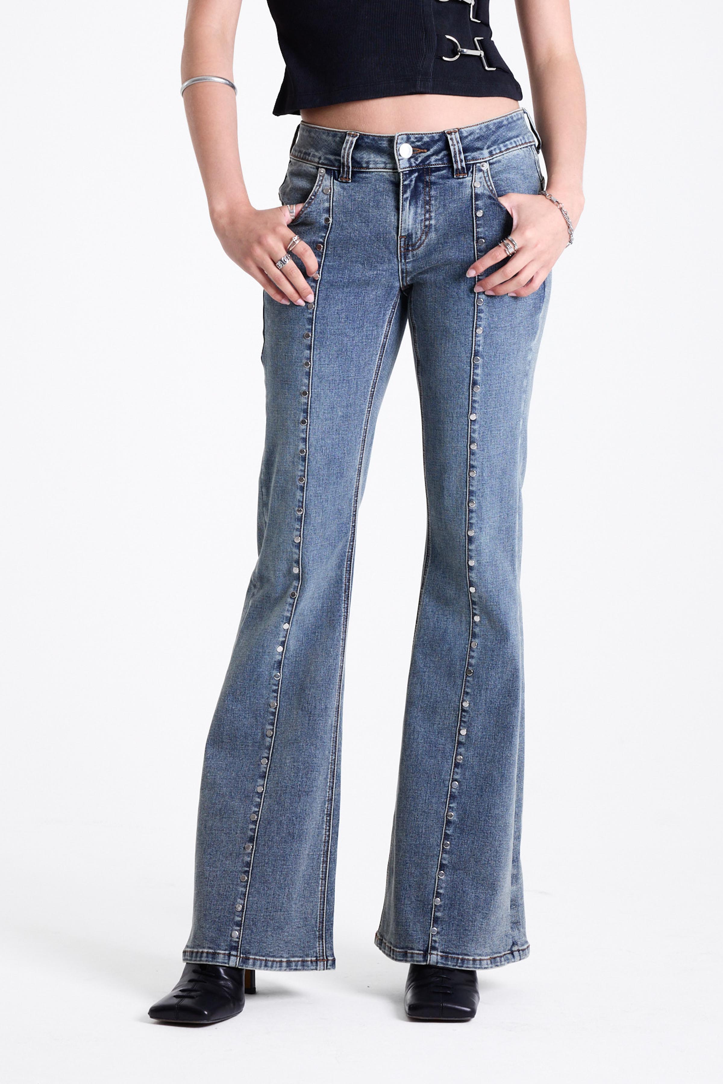 Vintage wash low rise flare jeans with exposed seam and stud detail, worn by model