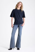 Vintage wash low rise flare jeans with exposed seam and stud detail, worn by model