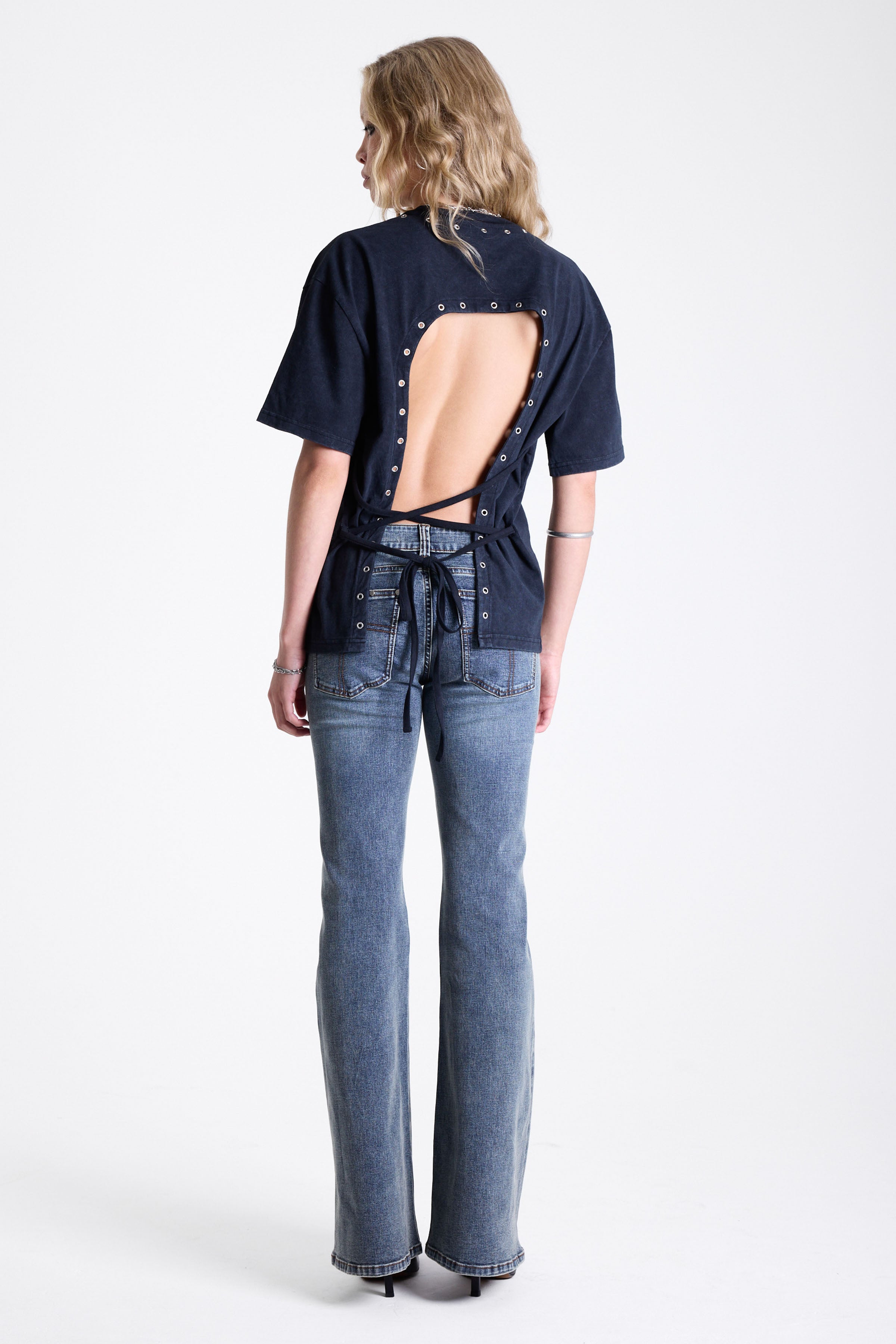 Vintage wash low rise flare jeans with exposed seam and stud detail, worn by model
