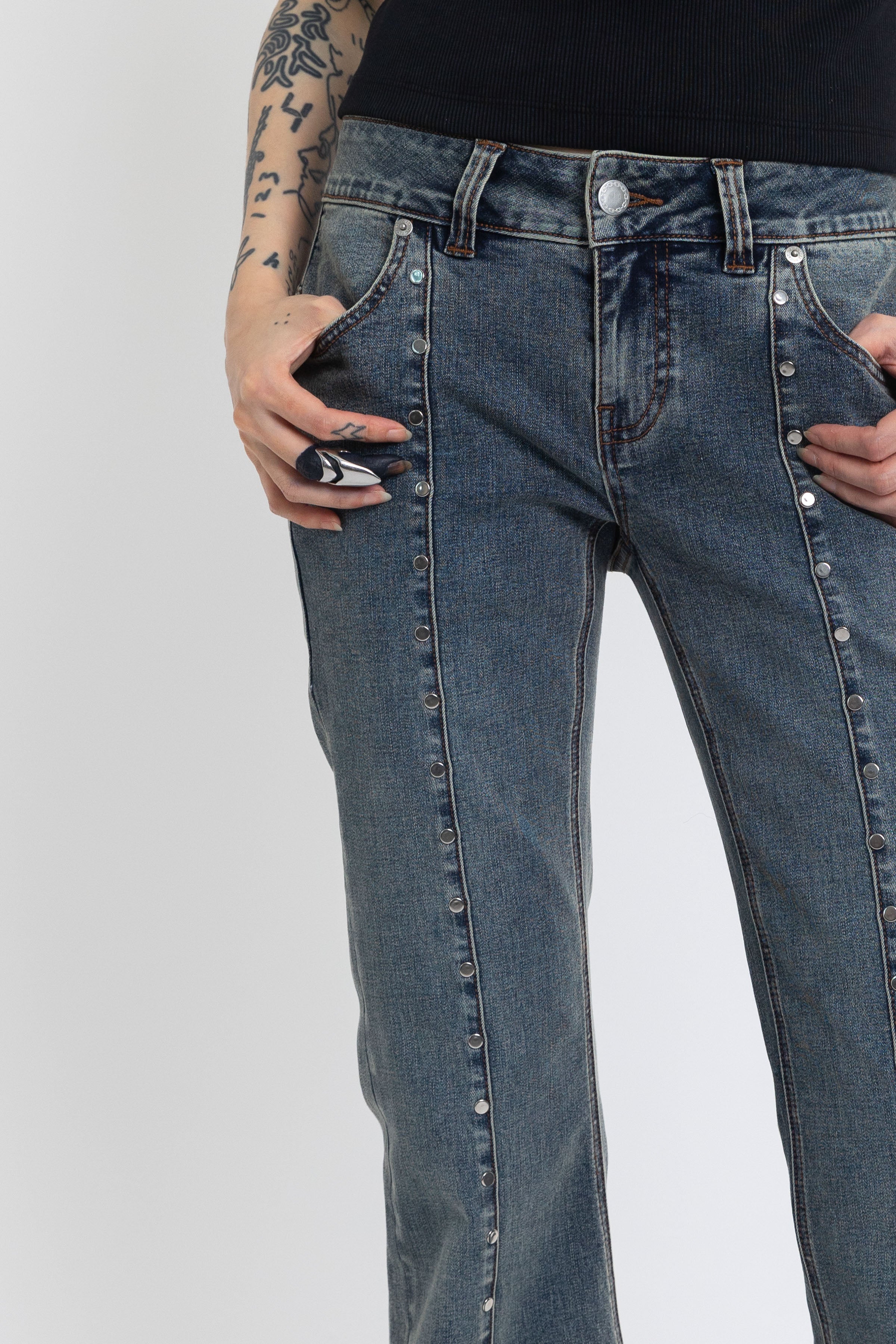 Washed denim low rise flare jeans with silver stud and front seam detail, worn by model