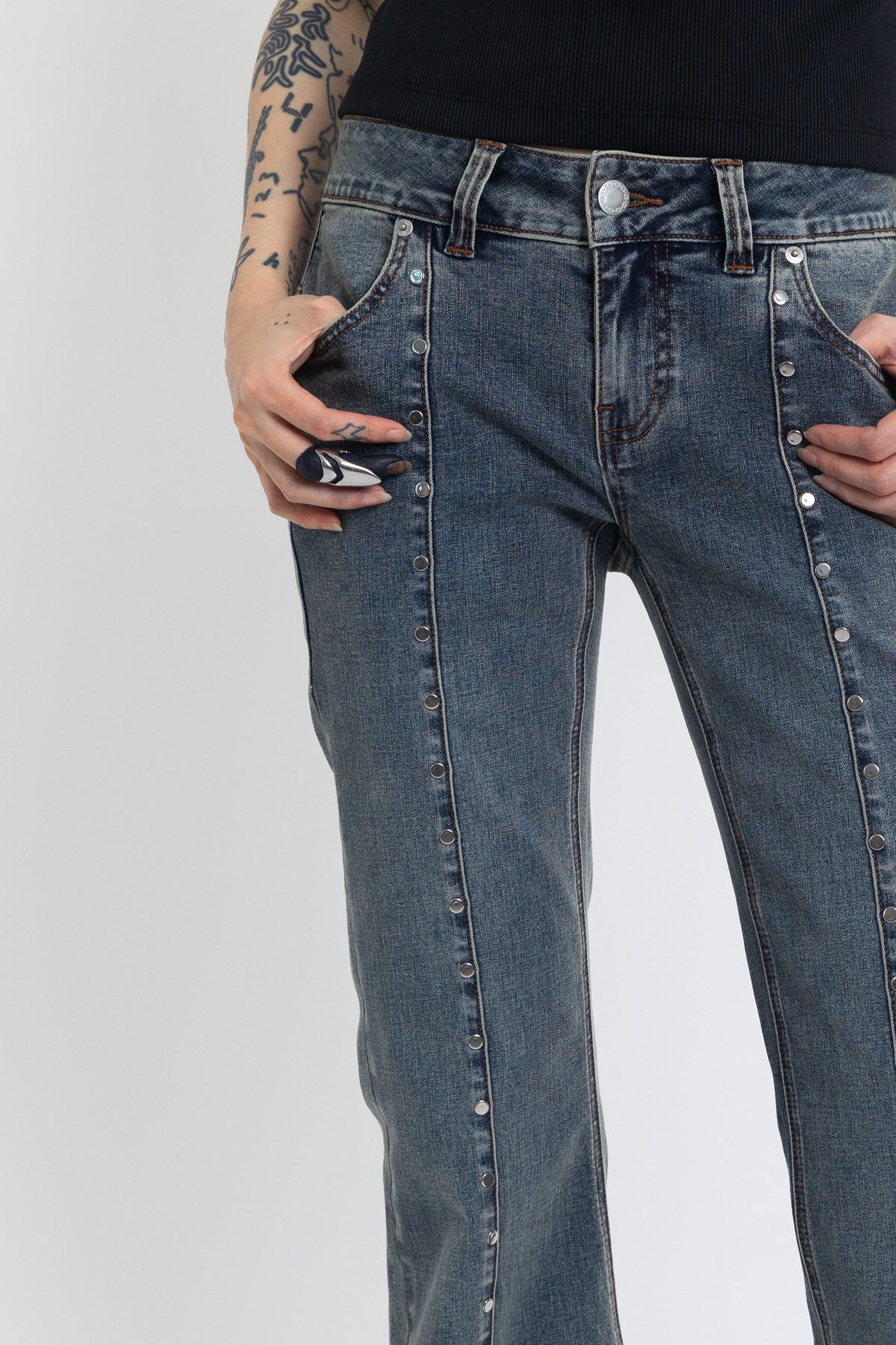 Washed denim low rise flare jeans with silver stud and front seam detail, worn by model
