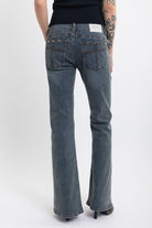 Washed denim low rise flare jeans with silver stud and front seam detail, worn by model