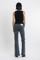 Washed denim low rise flare jeans with silver stud and front seam detail, worn by model