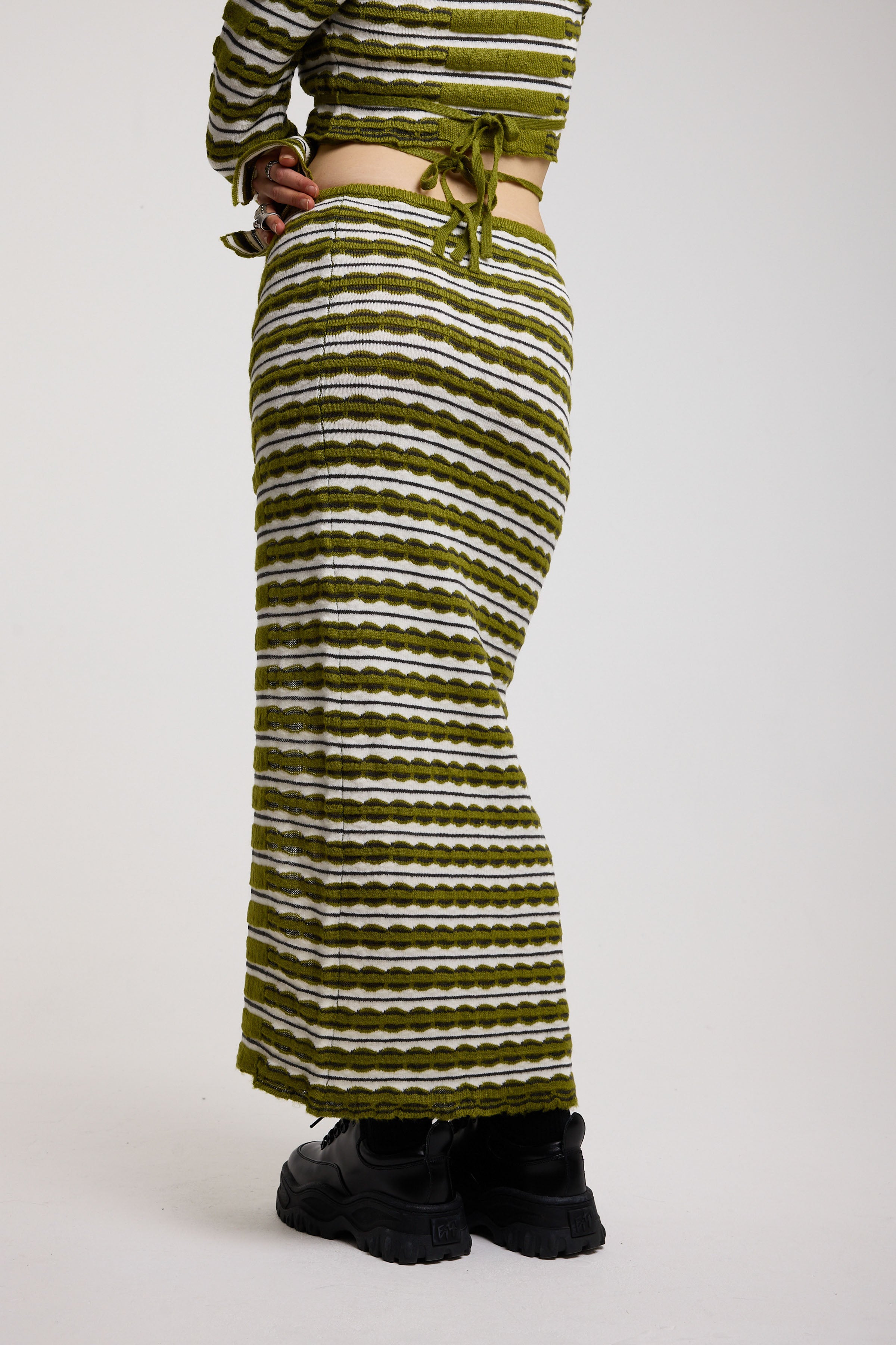 Green textured stripe knit maxi skirt with thigh high split and silver hardware detailing, worn as a co-ord by model