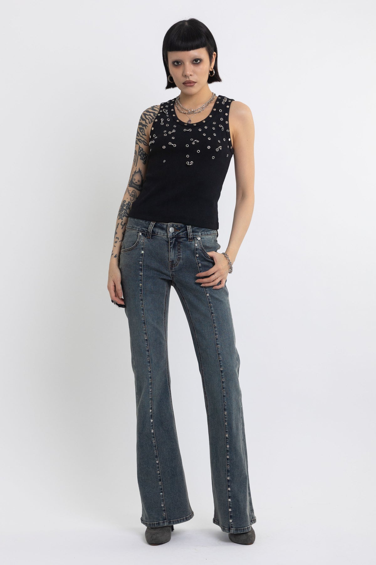Black tank top with silver eyelets and stud hardware, worn by model