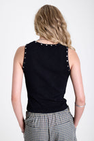 Black ribbed tank top with piercing and stud hardware details, worn by a model