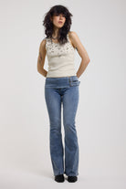 Ecru ribbed tank top with piercing and stud hardware details, worn by a model