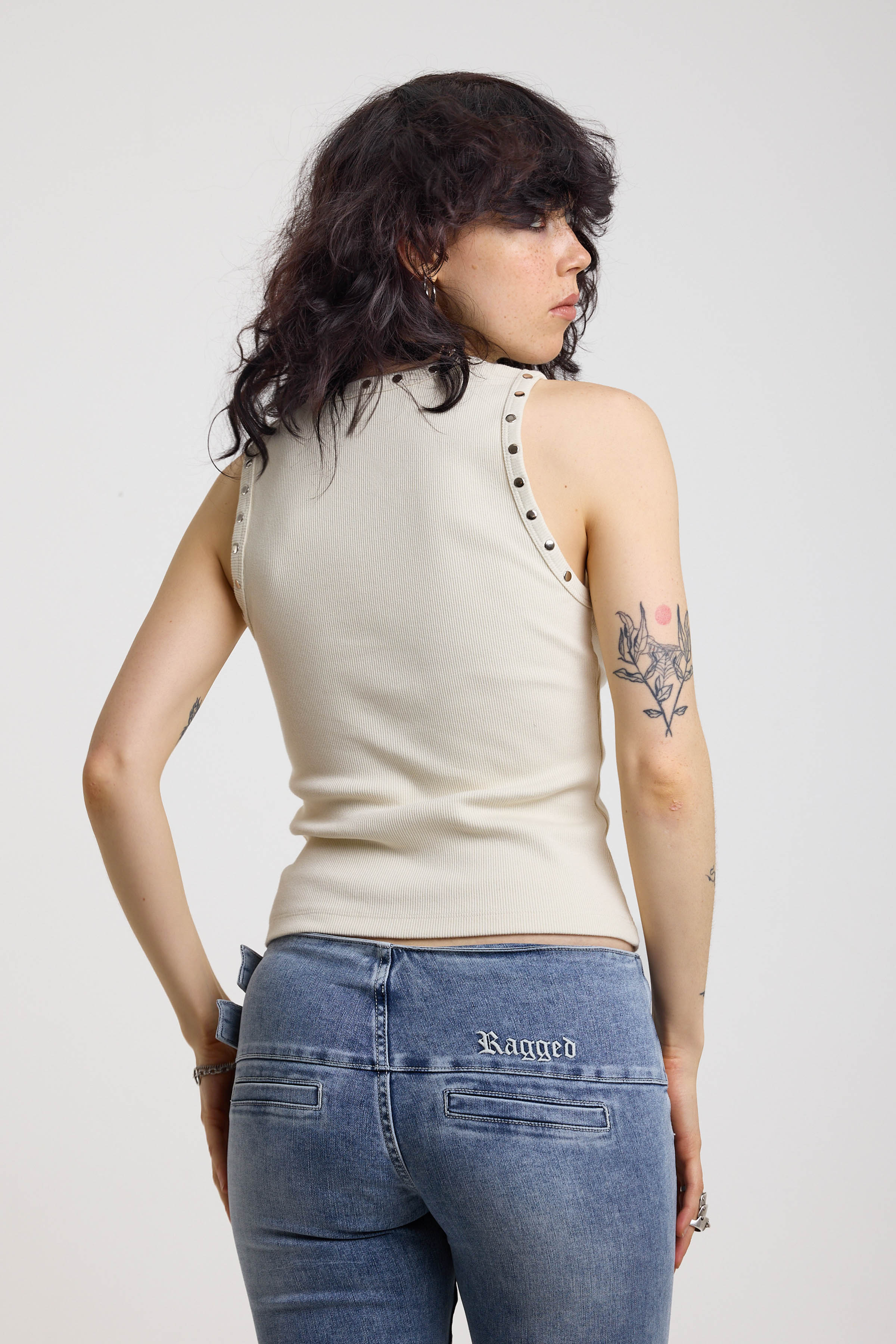 Back image of ecru ribbed tank top with piercing and stud hardware details, worn by a model