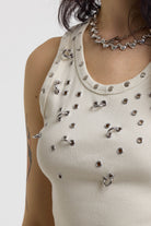 Close up of silver piercing, eyelet and stud details on cru ribbed tank top, worn by a model
