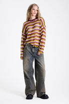 Dirty wash oversized baggy colossus jeans with silver and bronze stud hardware detail, worn by model