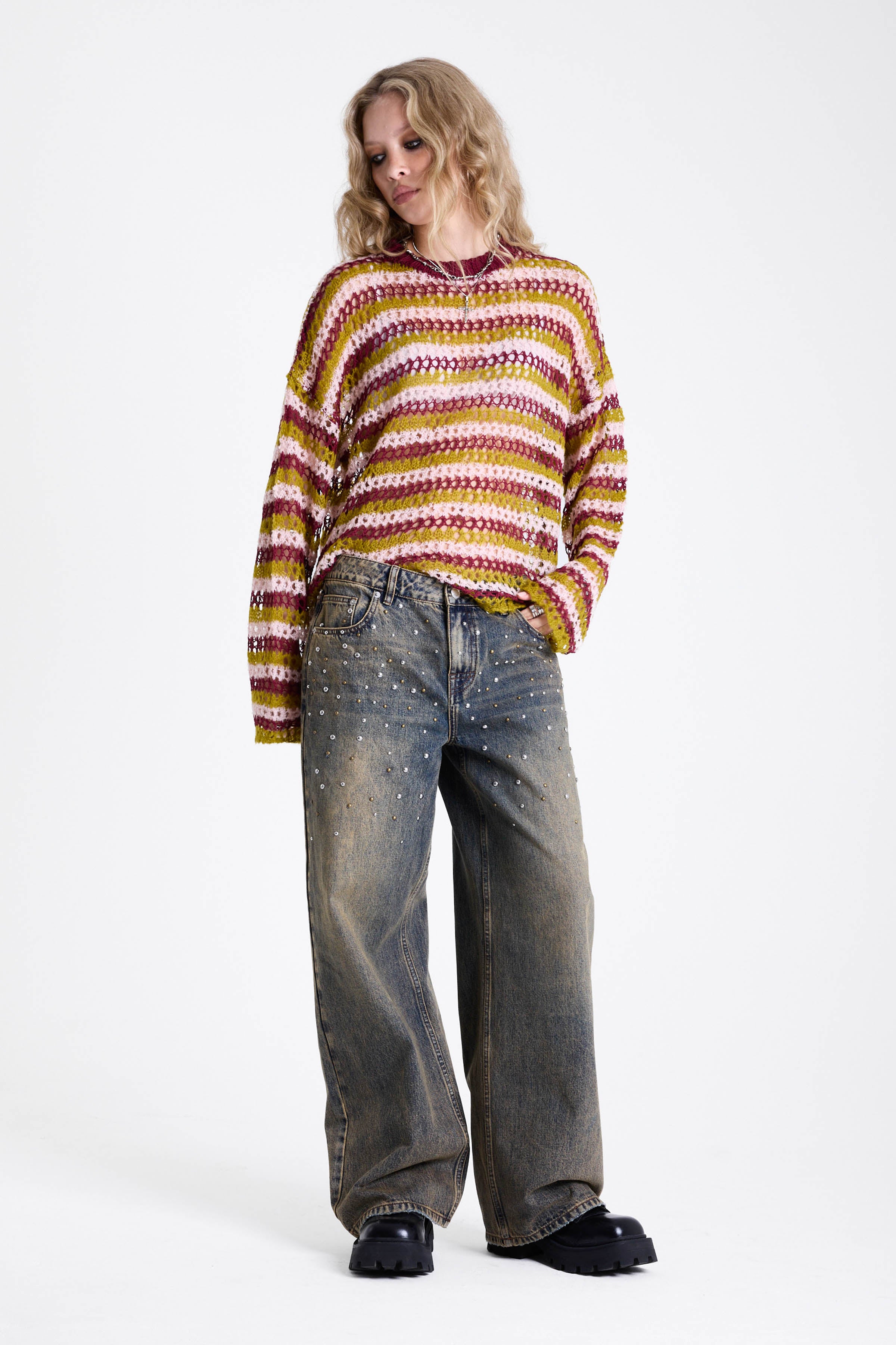 Dirty wash oversized baggy colossus jeans with silver and bronze stud hardware detail, worn by model