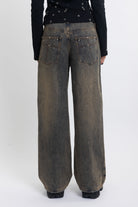 Dirty wash ultra baggy colossus jeans with scattered studs, worn by model