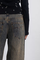 Dirty wash ultra baggy colossus jeans with scattered studs, worn by model
