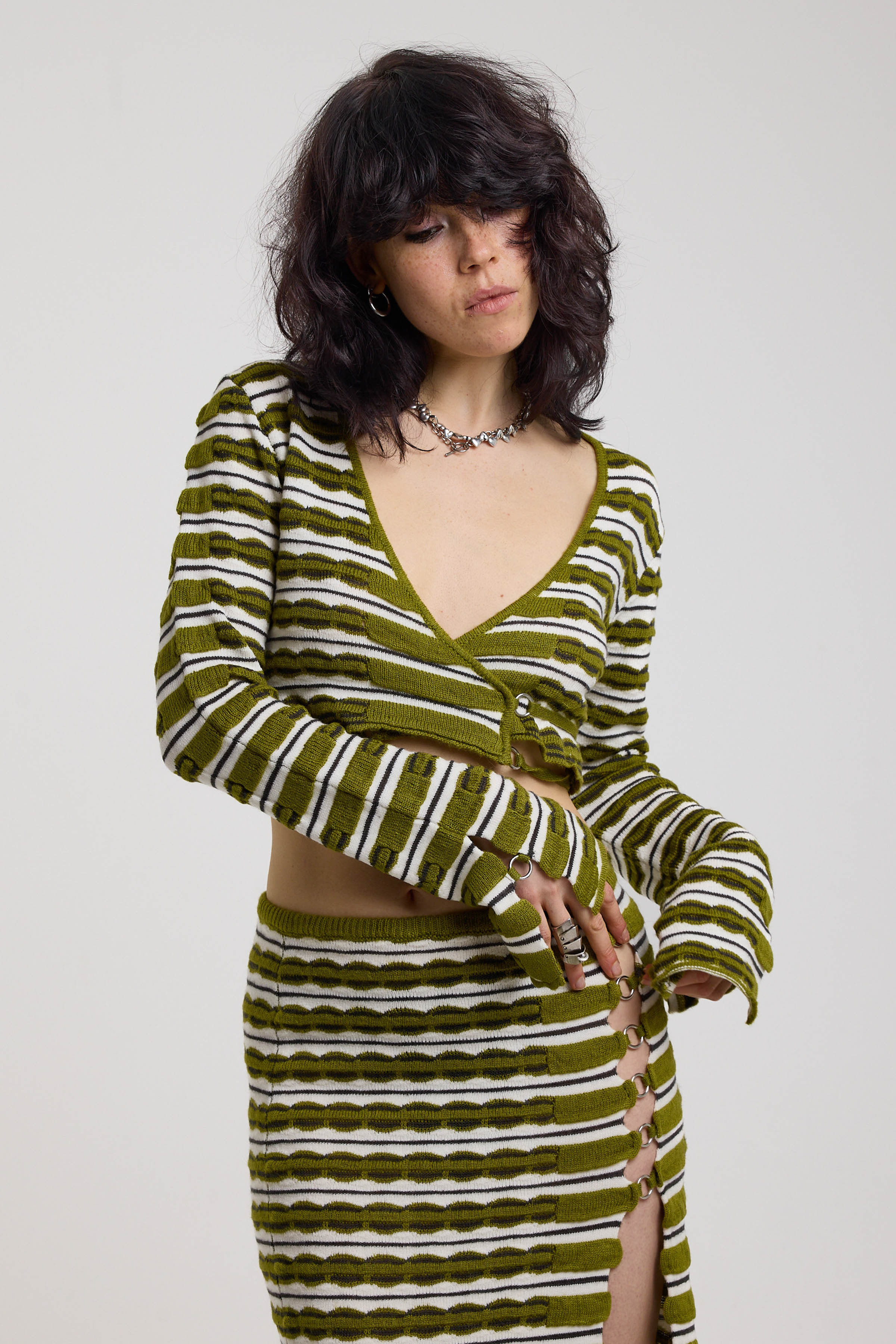 Green textured stripe wrap knit top with plunge neckline and silver hardware detailing, worn by model