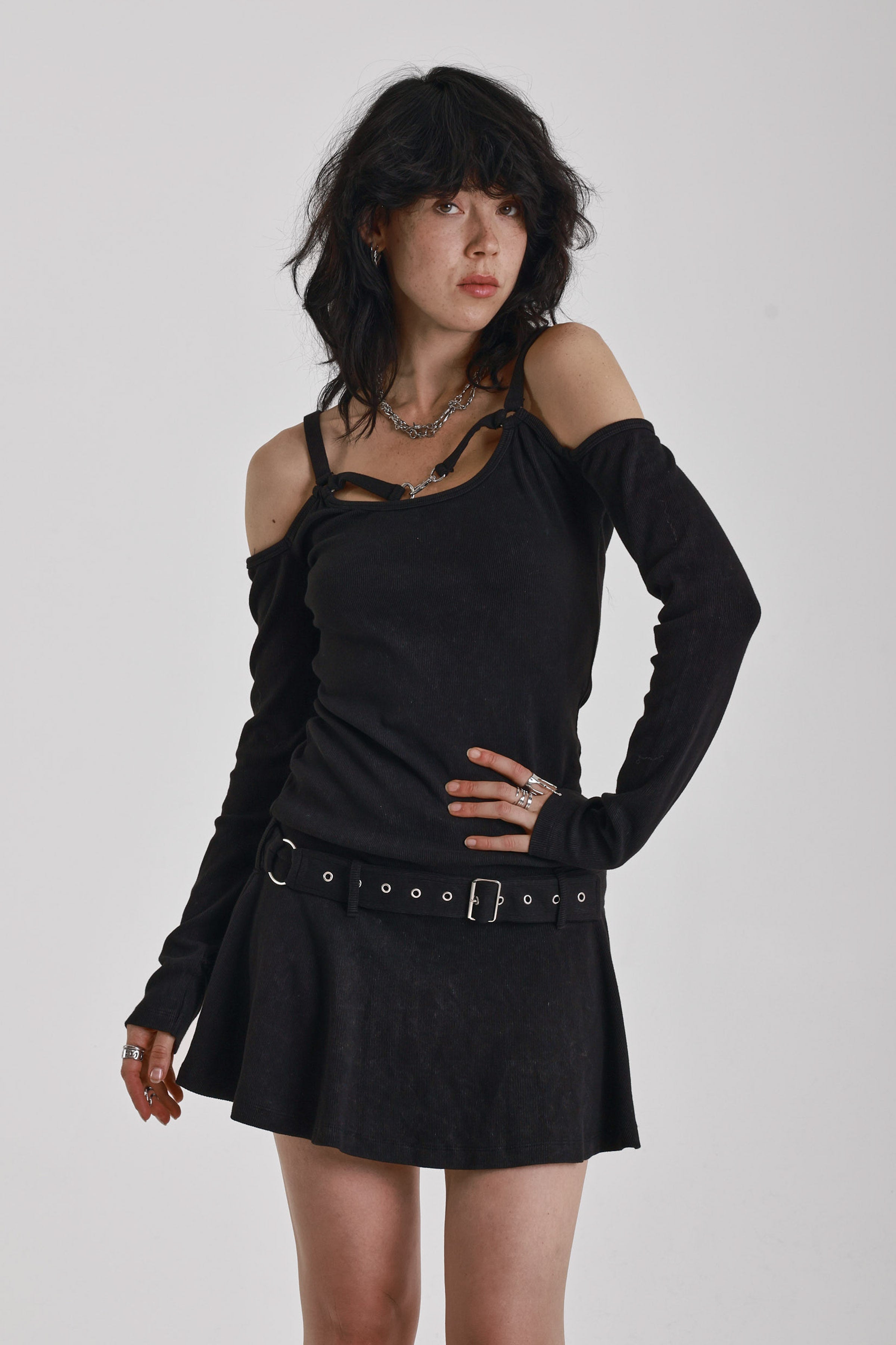 Washed black long-sleeve cold-shoulder mini dress with trigger clasp strap and eyelet belt, worn by model