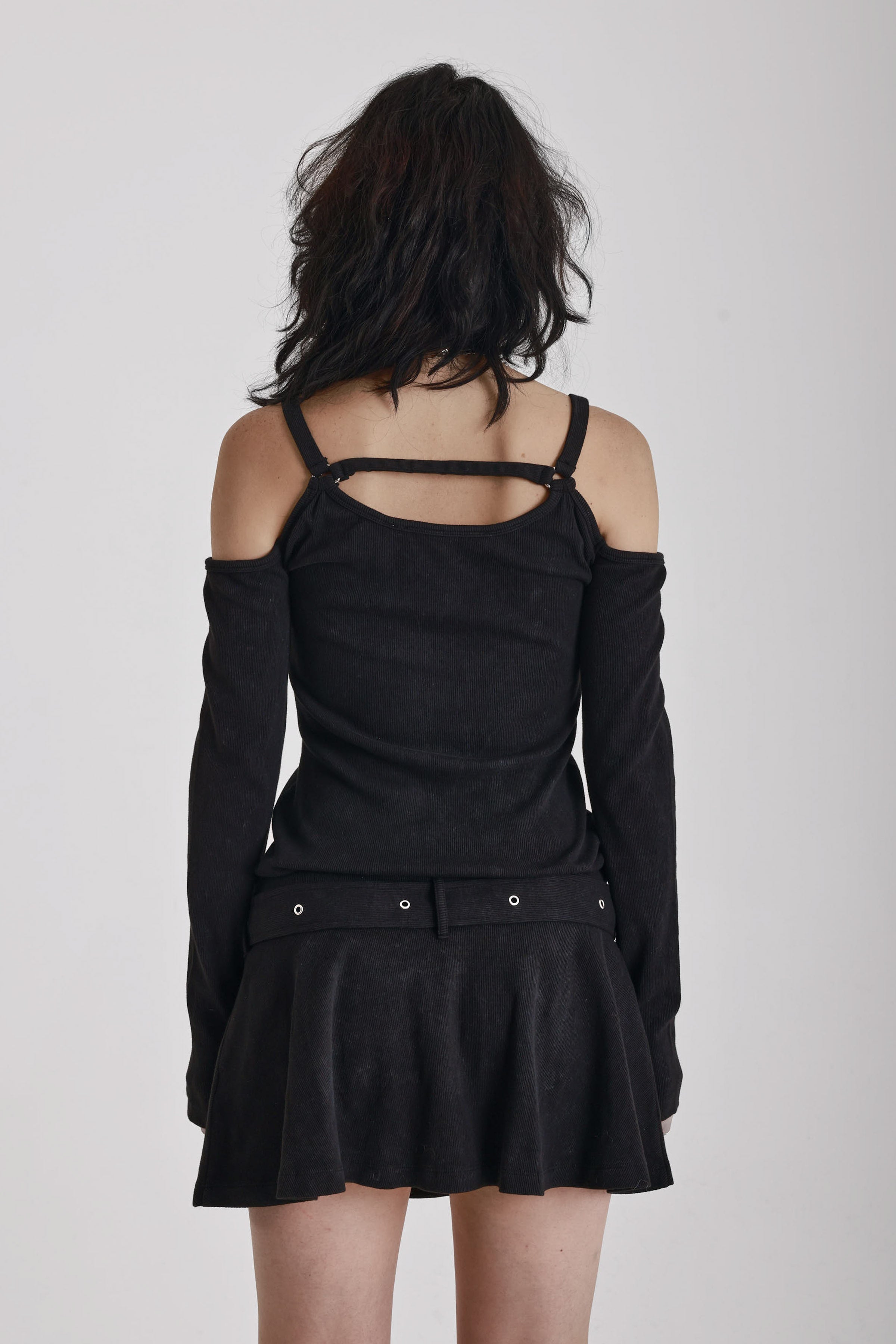 Washed black long-sleeve cold-shoulder mini dress with trigger clasp strap and eyelet belt, worn by model