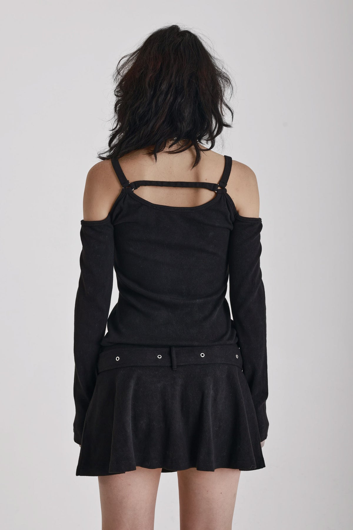 Washed black long-sleeve cold-shoulder mini dress with trigger clasp strap and eyelet belt, worn by model