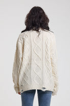 Back image of cream oversized cable knit jumper with distressed details, worn by model